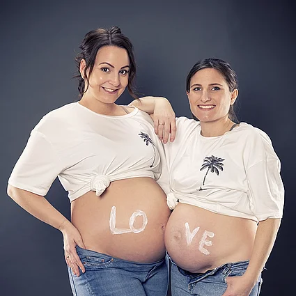 Zwei Babybäuche mit dem geteilten Schriftzug Love Zwei Babybäuche Schriftzug Love