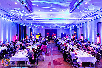 Eventraum von der Bühne aus mit Gästen an den Tischen Eventraum