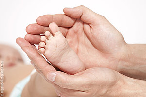 Foto vom Babyfuß in der Hand der Mutter Foto vom Babyfuß